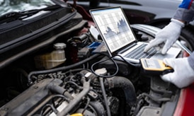 A picture of a laptop computer connected to a car engine.