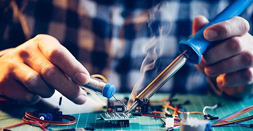 An electrical engineer working on a circuit board with a soldering iron