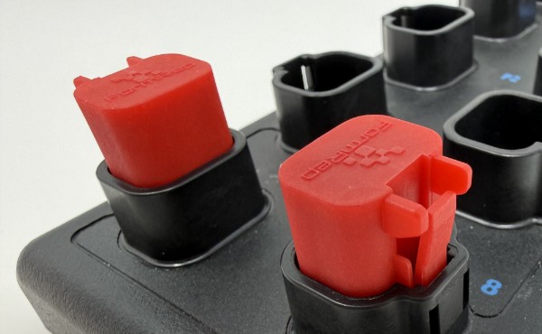 Image of FormRep Two red Socket Lock sealing plugs installed in unused DT-style ports on an I/O module